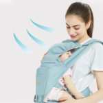Bébé dans son porte bébé endormi contre la poitrine de sa maman. Des vagues bleues en dessin montrent que la tête de bébé est protégée grâce au tissu. Sa maman le regarde avec amour et tendresse en souriant.
