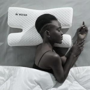 Oreiller ergonomique blanc à mémoire de forme pour préserver la peau du visage. Femme qui dort sur le côté bras levés.