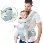 Porte bébé multifonctions vert porté par un papa avec un bébé dedans qui tire la langue.