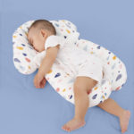 Matelas de positionnement ergonomique blanc à motif gouttes colorées. Bébé qui dort sur le côté gauche parfaitement paisible.