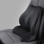 Coussin ergonomique de dos noir posé sur un siège de voiture gris.