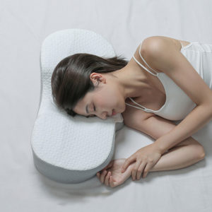 Oreiller ergonomique forme oval avec fille qui dort sur le côté.