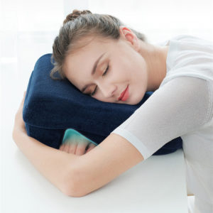 Oreiller de sieste à mémoire de forme bleu marine avec femme qui dort sur le côté bras sous le coussin.