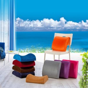 Des coussins ergonomique avec mousse à mémoire de forme colorés posés sur une chaise et sur un parquet avec un fond paradisiaque