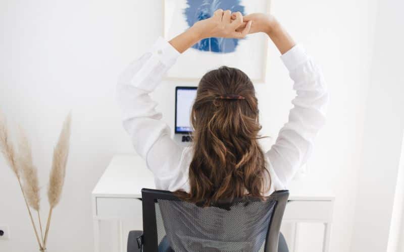 L'impact des produits ergonomiques sur la posture femme assise à son bureau qui s'étire les bras vers le haut