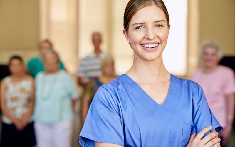 soignante avec un grand sourire et des personnes derrière elle