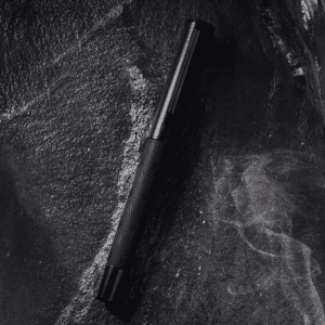 Stylo Ergonomique à Plume Haut de Gamme en Titane posé sur une pierre noire