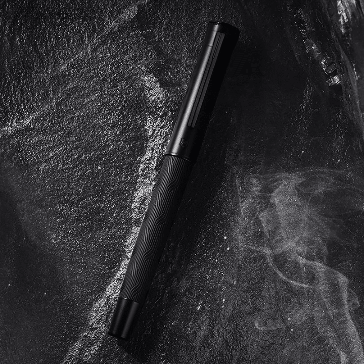 Stylo Ergonomique à Plume Haut de Gamme en Titane posé sur une pierre noire