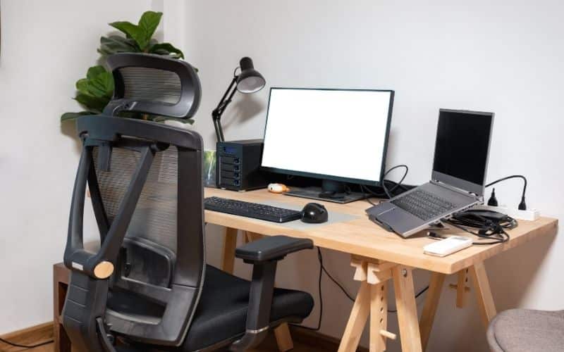 Bureau ergonomique, avec un siège ergonomique et deux ordinateurs, un fixe et un portable sur un support ergonomique.