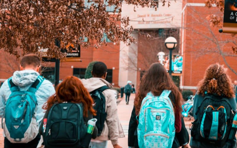 Les matériaux utilisés pour les sacs à dos ergonomiques Groupe de jeune de dos, portant tous un sac à dos et se dirigeant vers ce qui semble être une école.