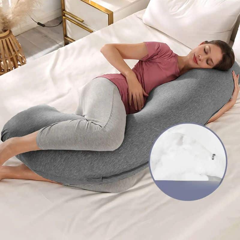 Oreiller de Grossesse Gris Confortable et Polyvalent dans un lit avec une femme qui dort dessus