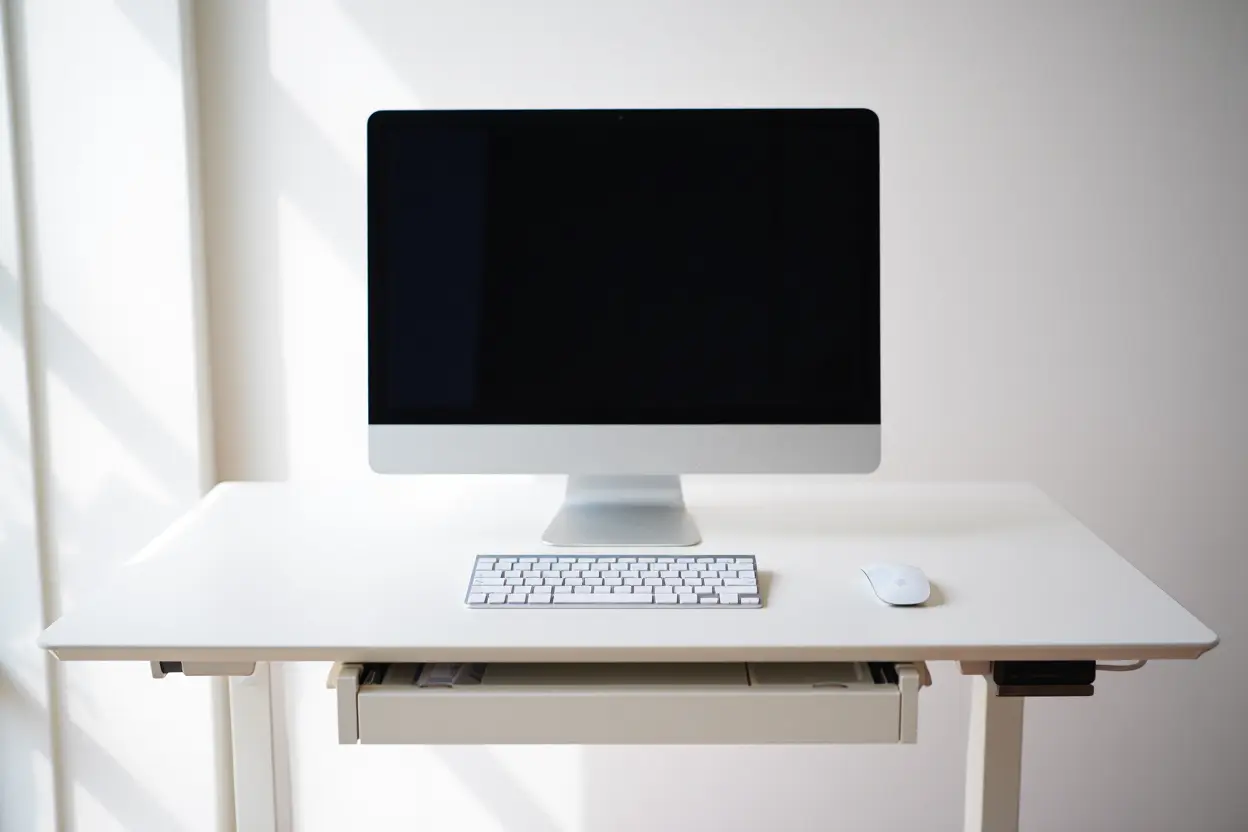 Faut-il utiliser un repose-poignet souris ? Ordinateur de bureau sur bureau blanc avec clavier et souris; tiroir partiellement ouvert sous le plateau. /* inclut la phrase clé naturellement sans forcer */ Faut-il utiliser un repose-poignet souris? image d’un espace de travail épuré.