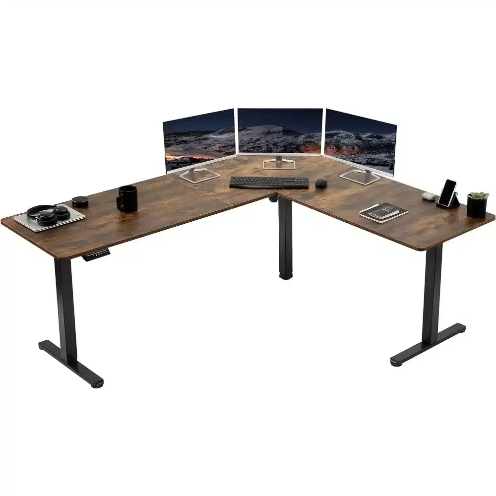 Bureau d’angle avec écran, clavier et accessoires sur plateau en bois posé sur deux pieds métalliques.