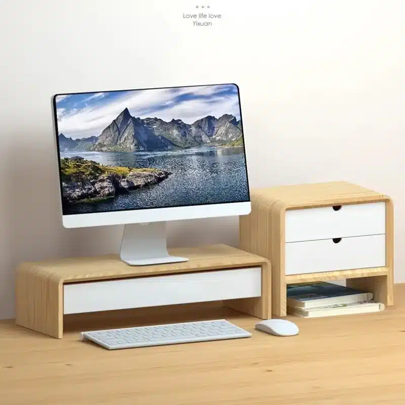 Comment organiser son bureau avec 2 écrans efficacement Un ordinateur et un clavier sur un meuble avec une petite étagère à côté, dans une pièce claire.